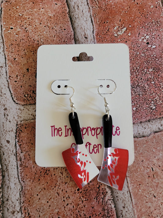 Pair of bloody butcher knife earrings on a card. 